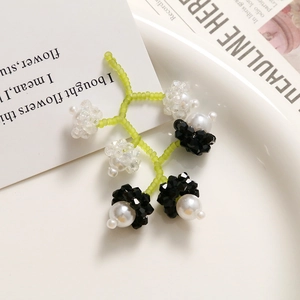 Détail de boucles d'oreilles faites main en perles vertes avec cristaux et fleurs blanches