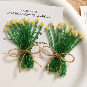 Handmade woven glass bead flower earrings with green stems and golden bow accents