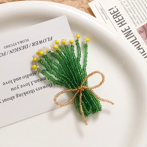 Macro shot of handmade beaded daisy flower bouquet with a bow on white ceramic plate