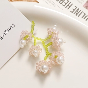 Détail de boucles d'oreilles en perles muguet faites main sur une assiette blanche