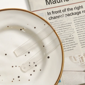 Detail shot of two transparent acrylic rectangular sticks on a white ceramic plate