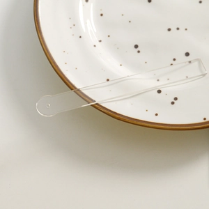 Macro shot of minimalist translucent acrylic strip accessory with hole on ceramic plate