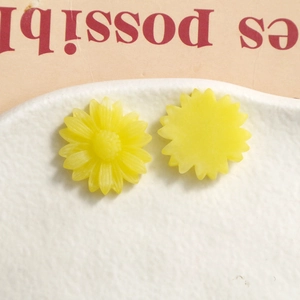 Macro shot of matte yellow resin sunflower charms for DIY hair accessories and crafts