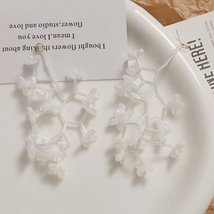 Detailed close-up of translucent pearlescent bellflower bead earrings on a ceramic dish