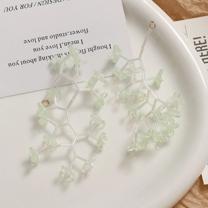 Detail of light green flower cluster earrings in a ceramic bowl with minimalist aesthetic