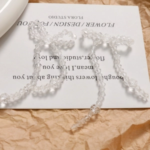 Dettaglio di orecchini a fiocco con perline in cristallo acrilico e lunghe nappe eleganti