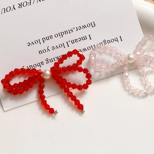 Detailed close-up of handmade bow-shaped beaded earrings with crystal beads and white pearls