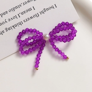 Close-up of handmade purple crystal beaded bow with white pearl accent and golden tips