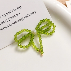 Detail of beaded green crystal bow earrings with pearls in elegant ceramic display