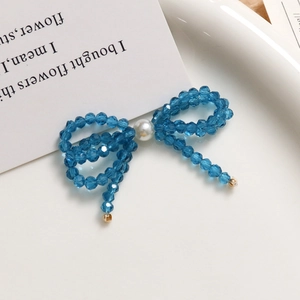 Detailed view of blue crystal bead bow with central pearl and golden accents on a white plate