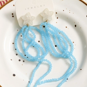 Long tassel earrings featuring white glitter stars and light blue translucent beads