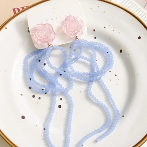Detail of handmade tassel earrings with pink resin roses and light blue beaded fringes