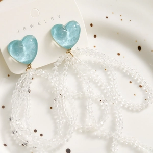 Detail of light blue heart resin drop earrings with long clear beaded tassels