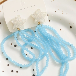 Detail of long tassel earrings with white star top and light blue beaded strands