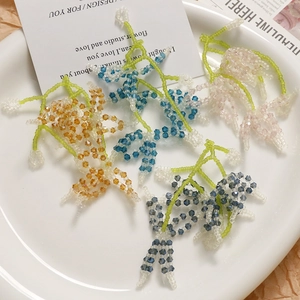 Handmade woven crystal flower earrings in four colors displayed on a white ceramic plate