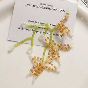 Macro detail of handmade crystal flower earrings with champagne and green glass beads