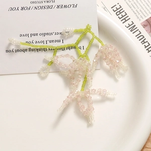 Detail shot of handmade lily of the valley beaded earrings with pink and white crystals