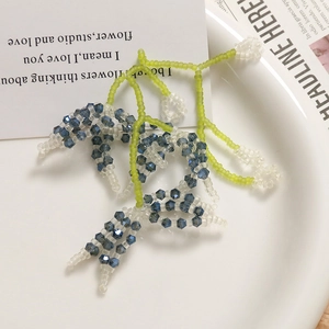 Detail of handmade woven floral cluster earrings with green and grey crystal beads