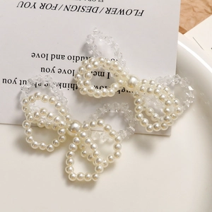 Détail macro de boucles d'oreilles nœuds faites main avec perles blanches et cristaux