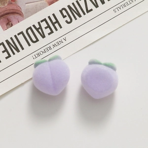 Macro detail of plush purple peach resin charms with soft flocking and green leaves