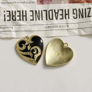 Detail of dark heart-shaped alloy pendants with black enamel and gold vine patterns