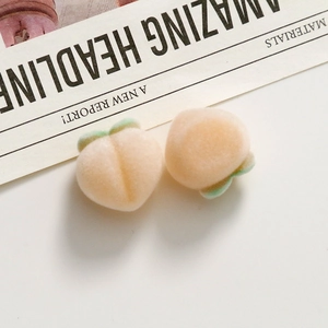 Close-up of peach-shaped flocked resin charms with green leaves for DIY jewelry making