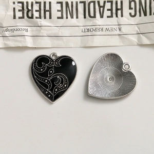 Detail of heart-shaped alloy pendant with black enamel and silver vine texture