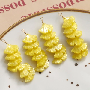 Macro shot of yellow acrylic ginkgo leaf pendants with golden glitter for DIY earrings