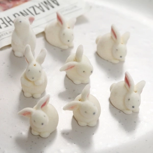 Close-up of small white flocked 3D bunny figurines for DIY crafts and accessories