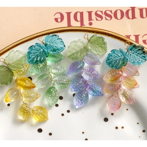 Pendientes artesanales con hojas y frutas degradadas en amarillo, verde, morado y rosa en plato