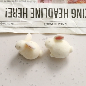Close-up of white flocked mini rabbit figurines with pink inner ears for DIY jewelry