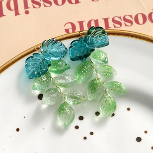 Detalle de pendientes de hoja de resina con degradado verde y pan de oro en plato cerámico