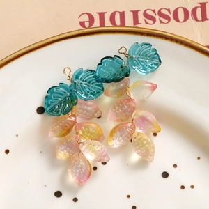Pendientes artesanales con hojas degradadas y bayas sobre un plato decorativo estético
