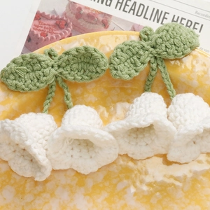 Detailed close-up of handmade crochet lily of the valley flowers with green leaves