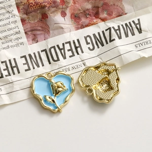Detail of blue enamel heart charm with gold rose relief and textured back for DIY jewelry