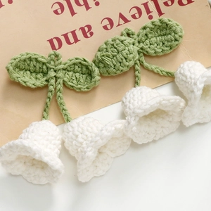 Detailed macro view of handmade crochet Lily of the Valley flower accessories with green leaves