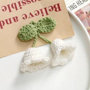 Macro view of handmade crochet lily of the valley flowers with green leaves and knitted texture