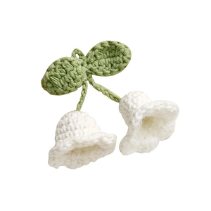 Detailed close-up of handmade crochet lily of the valley with green leaves and white flowers