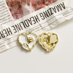 Detailed view of heart-shaped rose charms in gold and white enamel for jewelry making