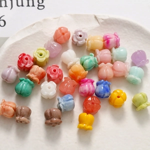 Nahaufnahme bunter Maiglöckchen-Perlen aus Kunstharz für DIY-Schmuck in einer weißen Schale