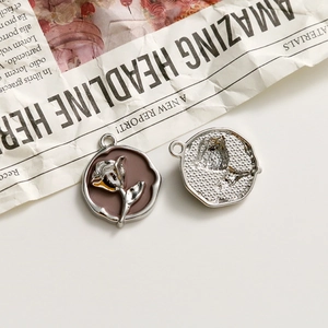 Detail of rose alloy charms showing silver flower engraving and starry back texture