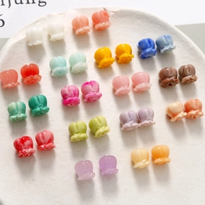 Bunte Kunstharzperlen in Maiglöckchenform für DIY-Schmuck auf einem weißen Keramikteller