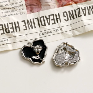 Macro view of heart-shaped alloy pendant with black enamel and silver rose relief detail