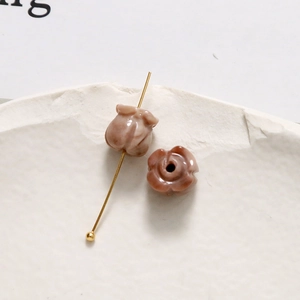 Makroaufnahme einer marmorierten Rosenknospen-Perle auf Goldstift für DIY-Schmuckzubehör