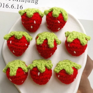 Macro shot of 8 handmade crochet strawberries with white dots for DIY crafts