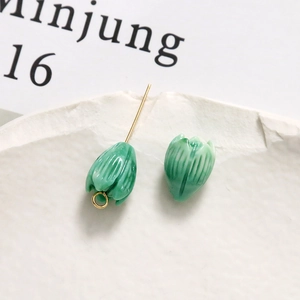Macro shot of green macaron flower beads and gold metal pins for DIY handmade jewelry