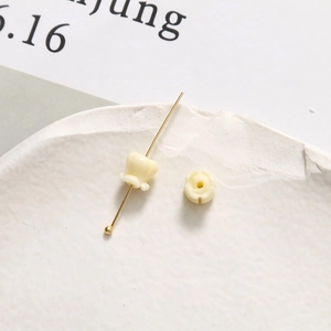 Makroaufnahme von 6mm Maiglöckchen-Perlen mit Goldnadel für DIY-Schmuckherstellung