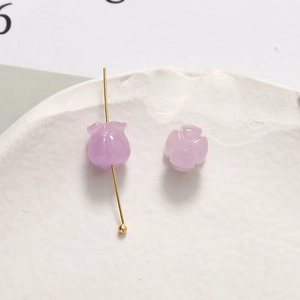 Makro-Detail einer zartvioletten Maiglöckchen-Perle aus Harz mit goldenem Metallstift