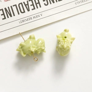 Detail van lichtgroene varkensbedeltjes van hars met gouden metalen pinnen voor DIY-sieraden
