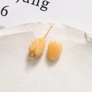 Macro detail of tulip-shaped cream resin pendant with gold metal pin for DIY jewelry making